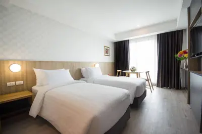 a hotel room with two beds and a table at Marsi Hotel @ Bangchak in Bangkok