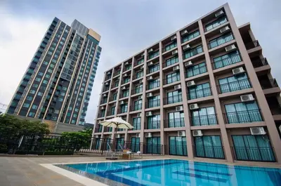 a hotel with a swimming pool in front of a building at Marsi Hotel @ Bangchak in Bangkok