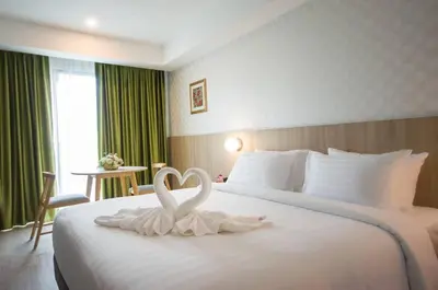 two white swans sitting on a bed in a hotel room at Marsi Hotel @ Bangchak in Bangkok