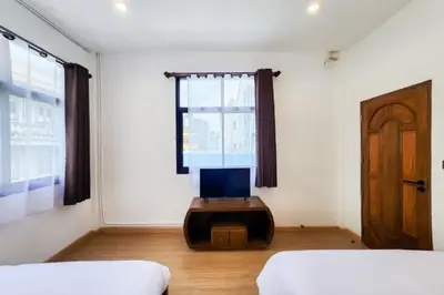a bedroom with two beds and a window and a tv at Taladnoi Paint House in Bangkok