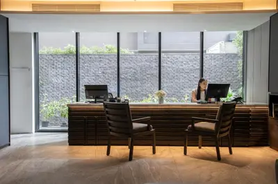 a woman sitting at a bar with a laptop at Walton Suites Sukhumvit in Bangkok