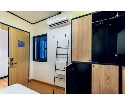 a room with a kitchen with a ladder and a refrigerator at Siam Subway Hostel and Café in Bangkok