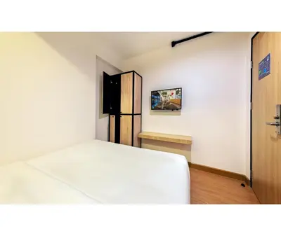 a bedroom with a white bed and a refrigerator at Siam Subway Hostel and Café in Bangkok
