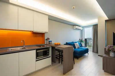 a kitchen with a table and a blue couch at Maitria Hotel Rama 9 Bangkok - A Chatrium Collection in Bangkok