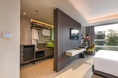 a bedroom with a bed and a desk and a bathroom at Maitria Hotel Rama 9 Bangkok - A Chatrium Collection in Bangkok
