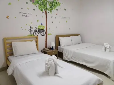 two beds in a room with a tree on the wall at ruamsab apartment1 in Bangkok