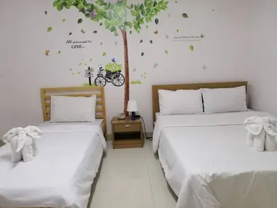two beds in a room with a tree on the wall at ruamsab apartment1 in Bangkok