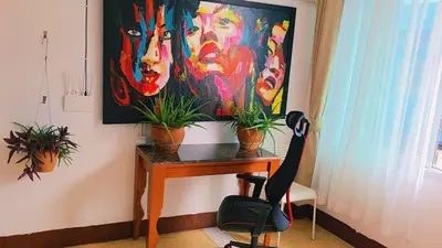 a painting on a wall above a table with plants at Lumphini 9 Haven Urban Retreat Bright Room in Bangkok