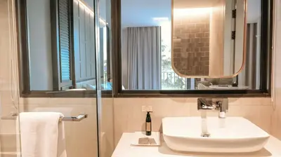 a bathroom with a sink and a mirror at The Quarter Ploenchit by UHG in Bangkok