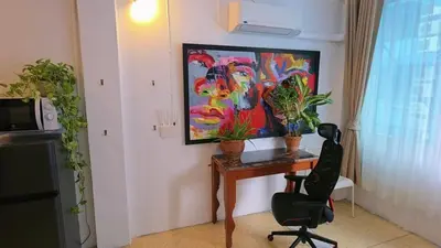 a desk with a chair and a painting on the wall at Lumphini 5 Train station center EnSuite Aircon in Bangkok