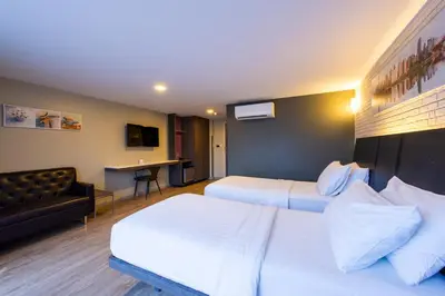 a hotel room with two beds and a couch at BB Glass House บีบี กลาสเฮ้าส์ in Bangkok