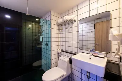a bathroom with a sink and a toilet and a mirror at BB Glass House บีบี กลาสเฮ้าส์ in Bangkok