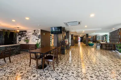 a hotel lobby with tables and chairs and a hallway at BB Glass House บีบี กลาสเฮ้าส์ in Bangkok