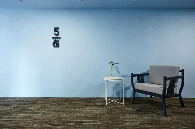 a blue wall with a chair and a table at 56 Surawong Hotel Bangkok in Bangkok