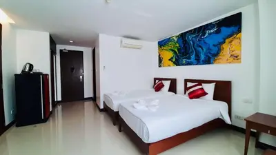 a bedroom with two beds and a painting on the wall at City Plaza Nana Hotel in Bangkok