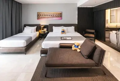 a bedroom with two beds and a couch with a teddy bear at S Ratchada Leisure Hotel in Bangkok