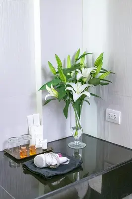 a vase with white flowers on a glass table at S Ratchada Leisure Hotel in Bangkok