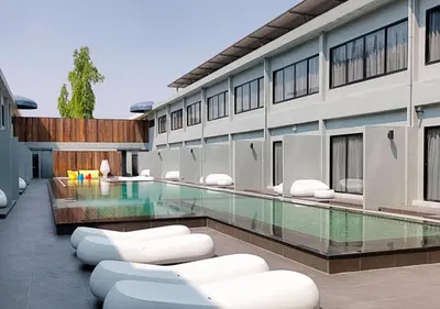a building with a swimming pool with white chairs at S Ratchada Leisure Hotel in Bangkok