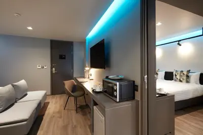 a hotel room with a bed and a desk with a microwave at The Quarter Silom by UHG in Bangkok