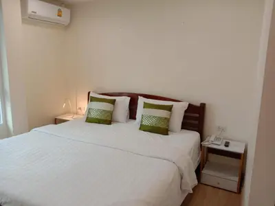a bedroom with a large white bed with green pillows at V Check inn Sukhumvit 22 in Bangkok
