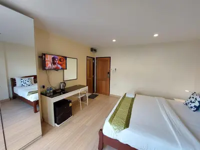 a room with two beds and a desk and a tv at V Check inn Sukhumvit 22 in Bangkok