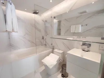 a white bathroom with a toilet and a sink at ashley hotel bkk in Bangkok