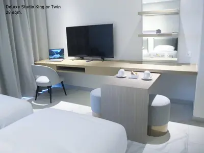 a room with a desk with a tv and chairs at ashley hotel bkk in Bangkok