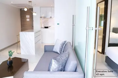 a living room with a couch and a kitchen at ashley hotel bkk in Bangkok