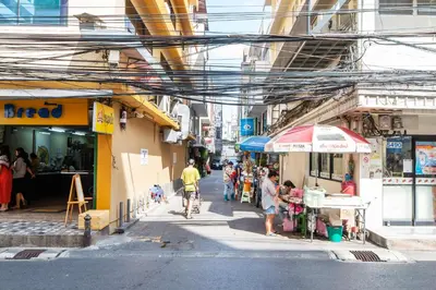 a man riding a bike down a street next to shops at The Mellow at Silom in Bangkok