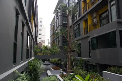 a courtyard between two buildings with a tree in the middle at iSanook Bangkok in Bangkok