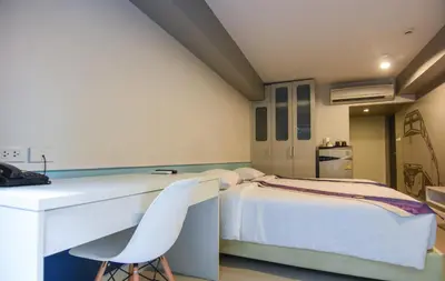 a bedroom with a bed and a desk and chairs at iSanook Bangkok in Bangkok