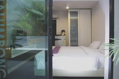 a bedroom with a white bed and a glass wall at iSanook Bangkok in Bangkok