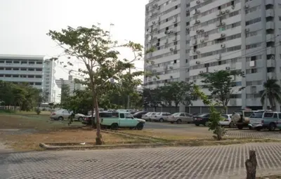 a parking lot with cars parked in front of a large building at MT-Room in Bangkok