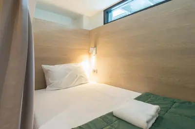 a bedroom with a bed with a pillow and a window at T Hostel @ Victory Monument in Bangkok