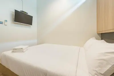 a bedroom with a white bed and a tv on the wall at T Hostel @ Victory Monument in Bangkok