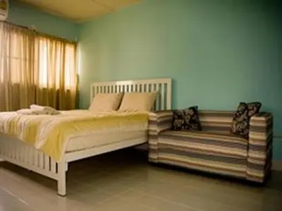 a bed and a couch in a bedroom at DMK Don Mueang Airport Guest House in Bangkok