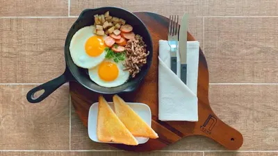 a frying pan with eggs and bread on a table at Krung Boutique Hotel in Bangkok