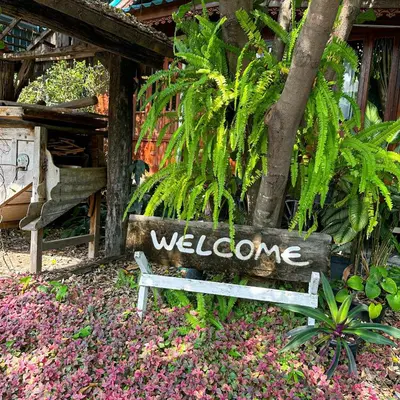 a bench with welcome written on it in flowers at โรงแรมบ้านเพิ่มสุข อิมแพ็ค เมืองทอง in Pak Kret