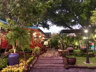 a garden in front of a house at night at โรงแรมบ้านเพิ่มสุข อิมแพ็ค เมืองทอง in Pak Kret
