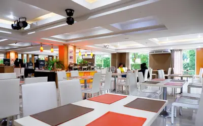 a restaurant with white tables and white chairs at The Wing Design Hotel in Bangkok