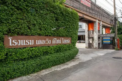 a sign on a bush in front of a building at The Wing Design Hotel in Bangkok