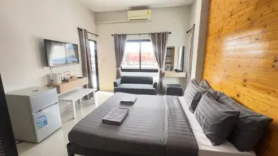a bedroom with a bed and a chair and a television at Buathong Pool Villa in Ban Khung Taphao