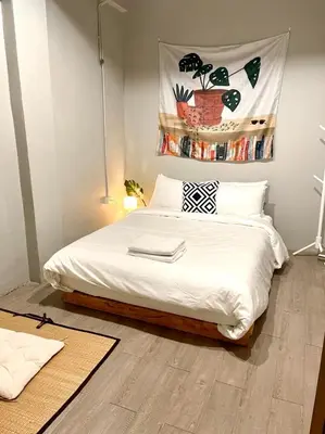 a bedroom with a bed with white sheets and a poster on the wall at Bangpho Story in Bangkok
