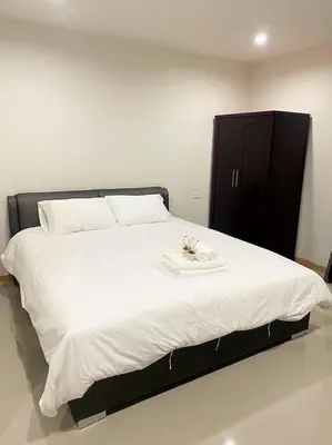 a large white bed with a black cabinet in a room at Re Riva in Ban Bang Bamru