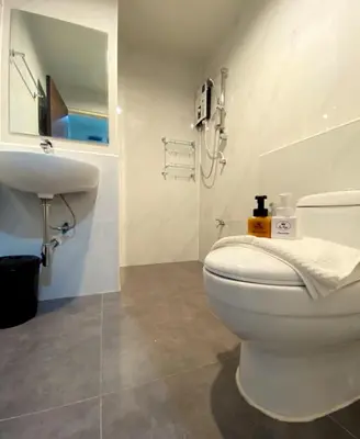 a bathroom with a white toilet and a sink at Re Riva in Ban Bang Bamru