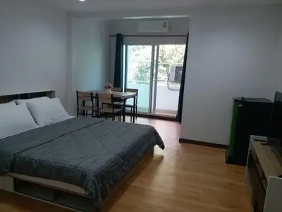 a bedroom with a bed and a table and a dining room at DD Garden Apartment 2 in Bangkok