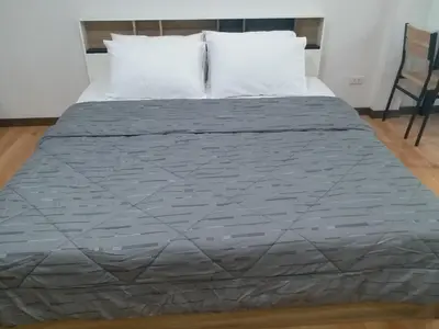 a bed with a gray comforter and two pillows at DD Garden Apartment 2 in Bangkok