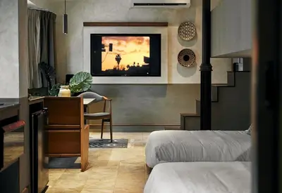 a bedroom with two beds and a desk and a table at B House 49 Bangkok in Bangkok