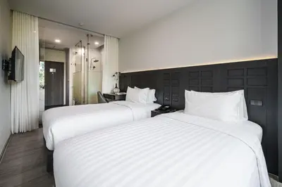 two beds in a hotel room with white sheets at VIX Bangkok at Victory Monument in Bangkok