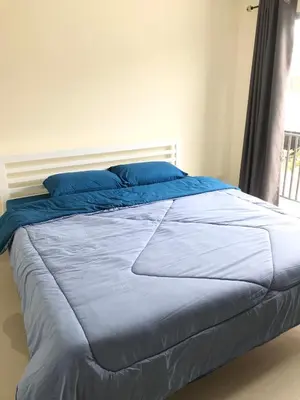 a bed with blue sheets in a bedroom with a window at Impact MT House in Ban Bang Phang